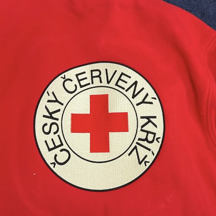 Velká výšivka znaku Českého červeného kříže na zádech červené mikiny